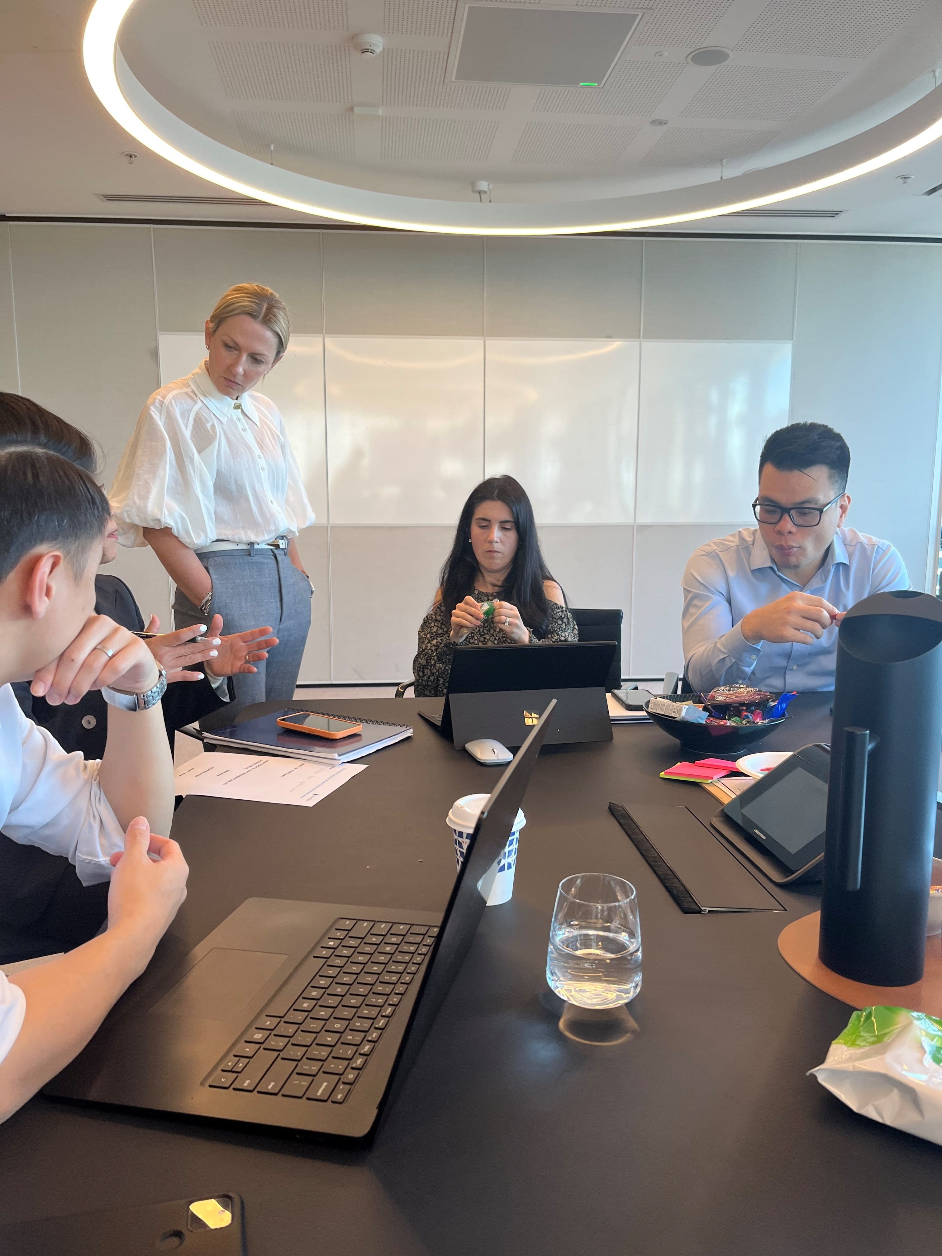 group sitting around table on laptops