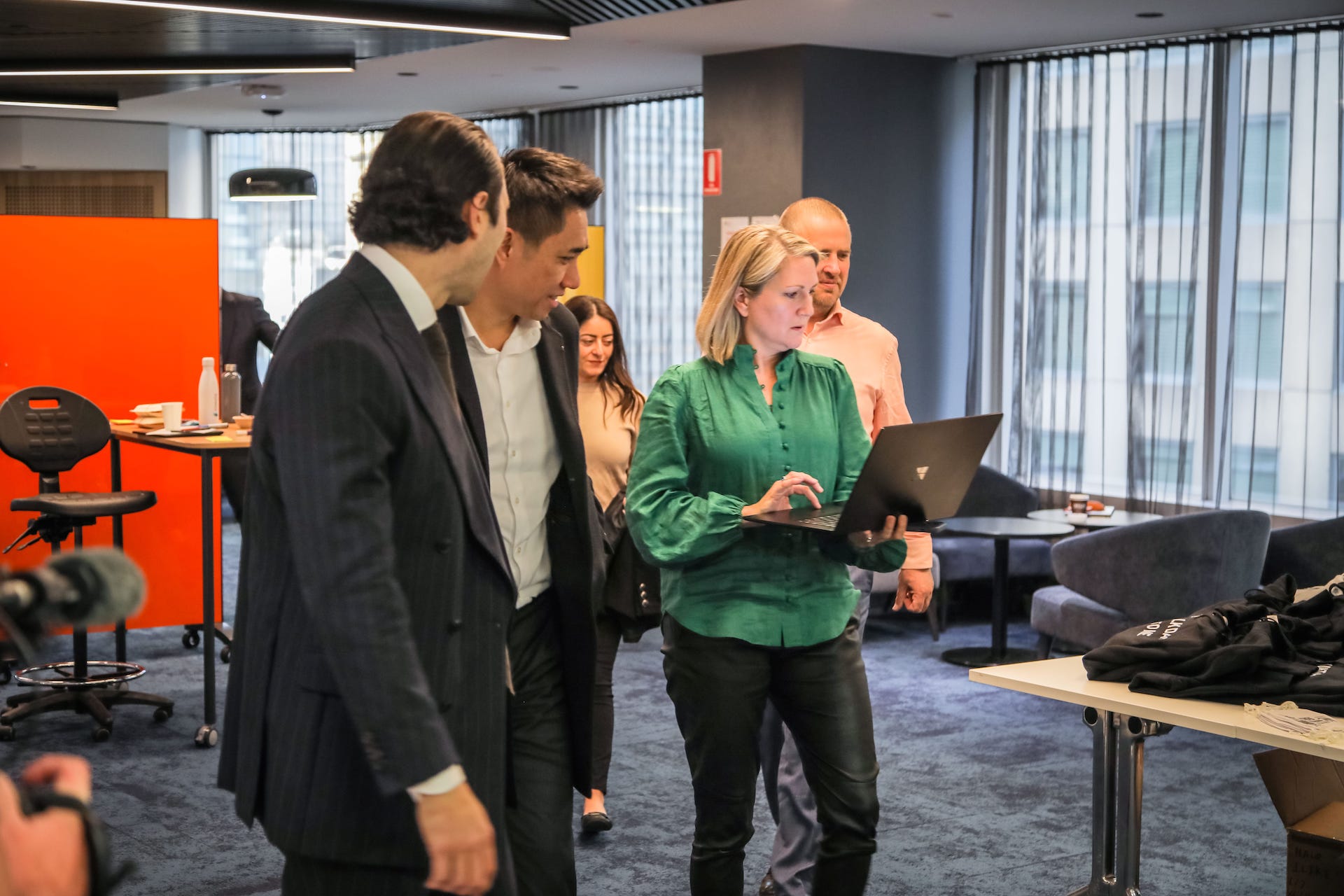 Senior leaders stand holding laptop